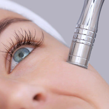Close-up of a person receiving a microdermabrasion treatment with a handheld device.